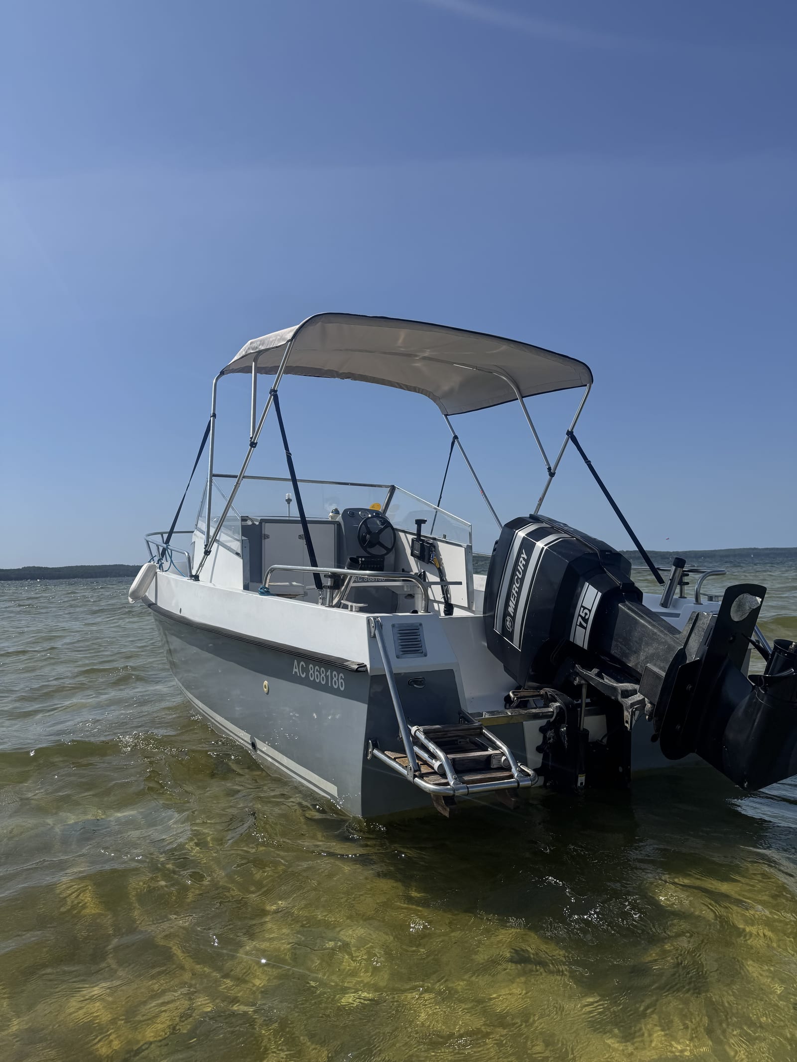 Le taud pare-soleil déployé au-dessus du cockpit du bateau, vu depuis le lac